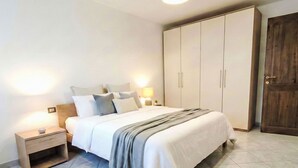 Een slaapkamer met een bed, nachtkastjes, een kledingkast en een deur.