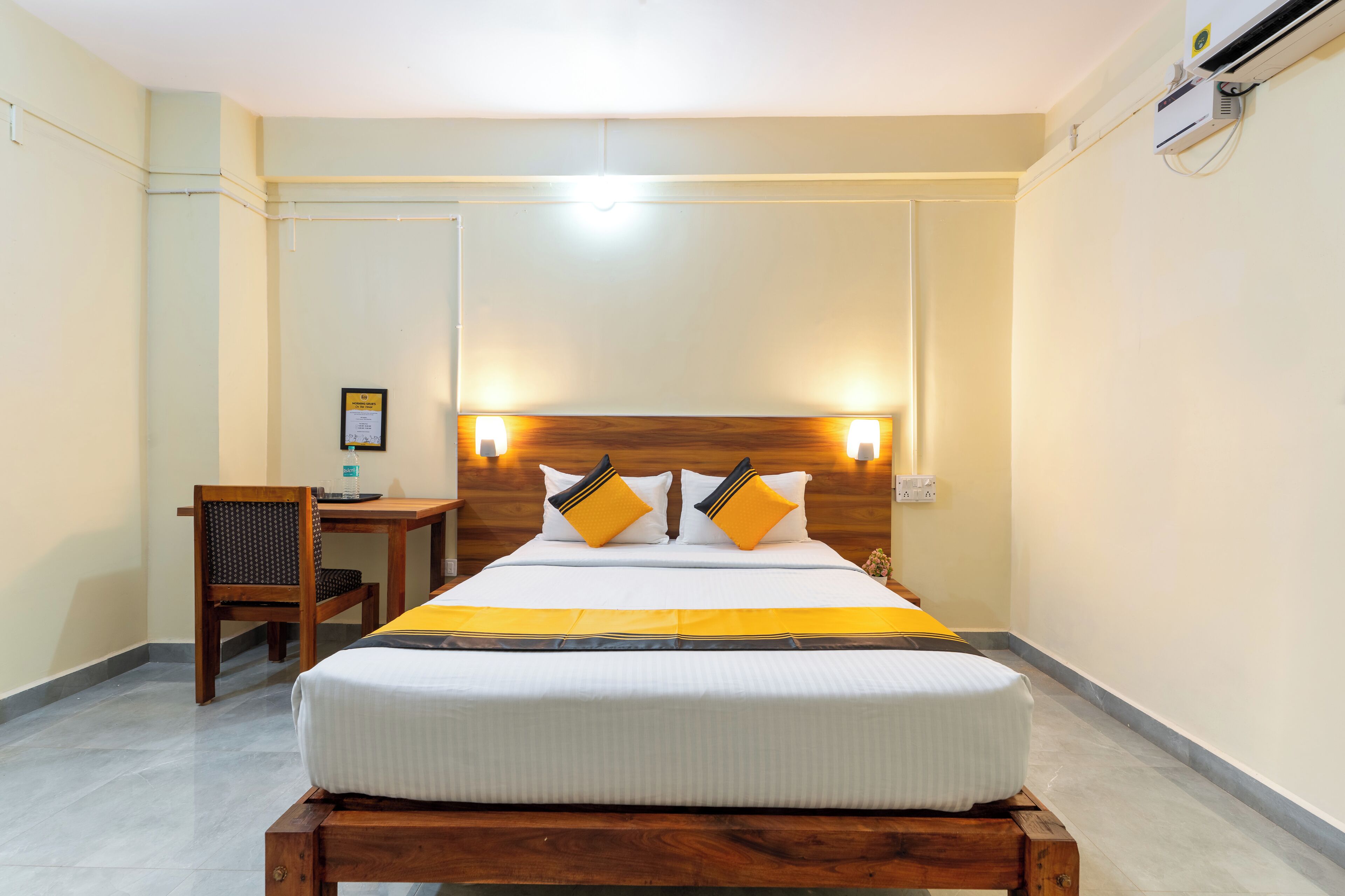 Ein Hotelzimmer mit Bett, Nachttisch, Stuhl und einer Wand-Klimaanlage.