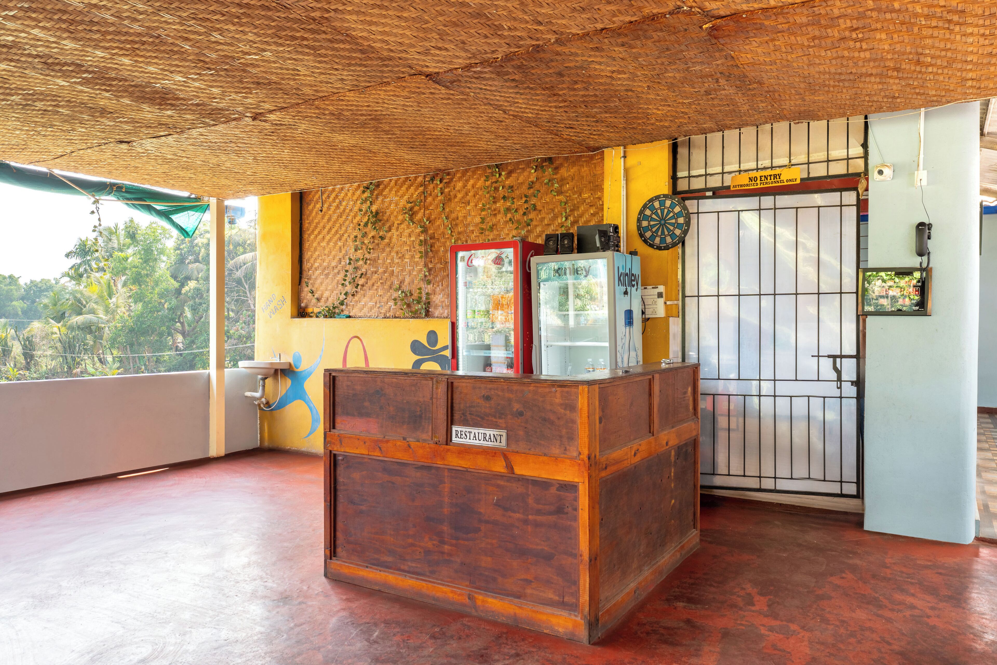 Un restaurante con mostrador de madera, dardos y una puerta cerrada con un letrero de 'Prohibido el paso'.