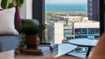 A view from a window overlooking a cityscape with modern buildings and a body of water.