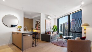 A modern apartment with a kitchen, living area, and large windows offering city views. - Queensbridge Luxe Living Next to Crown on the River. Pool • Gym • Sauna Steam (Southbank)