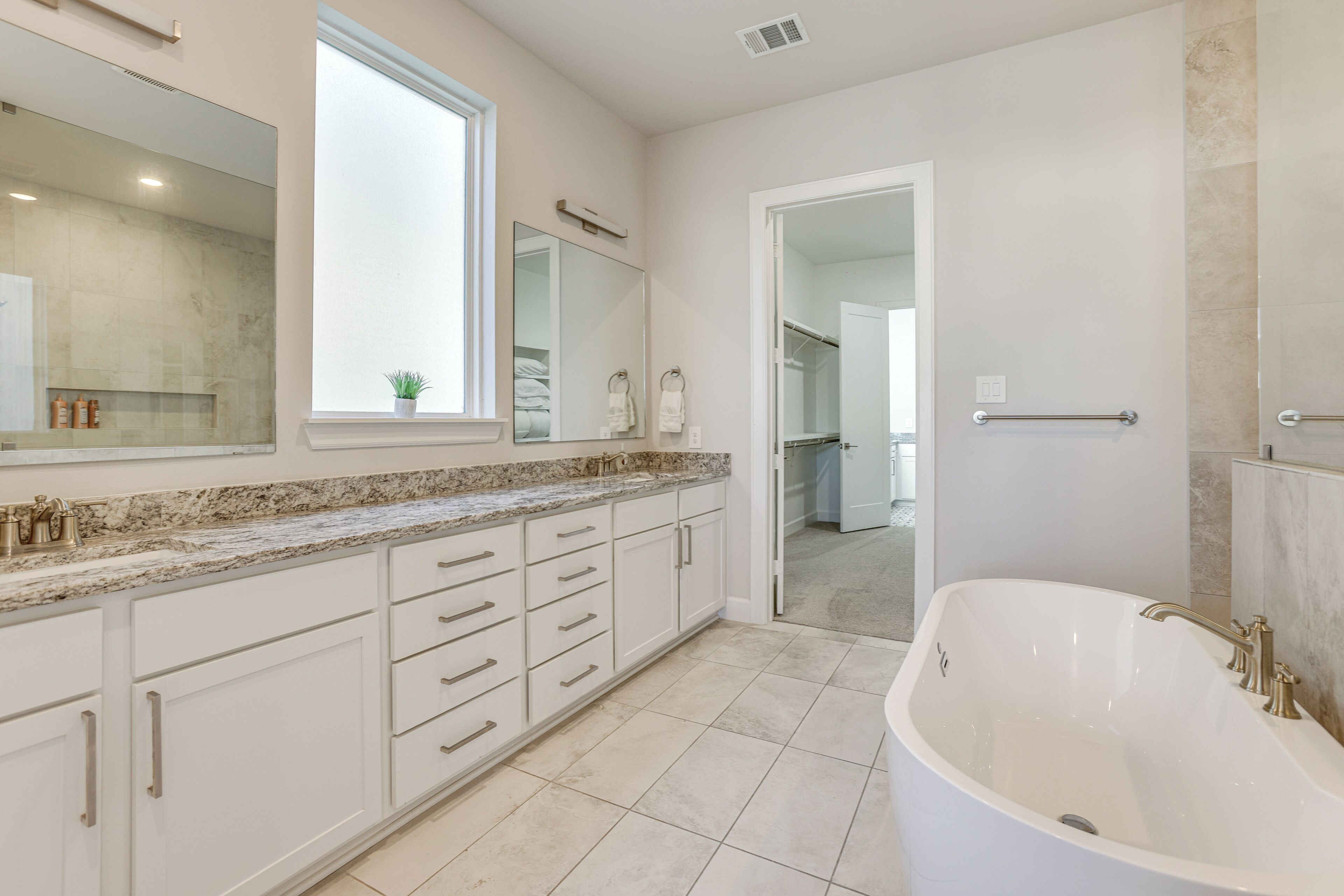 A modern bathroom with a freestanding bathtub, a large mirror, and a window.
