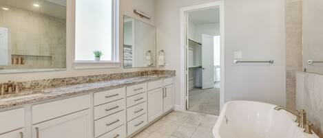 A modern bathroom with a freestanding bathtub, a large mirror, and a window.