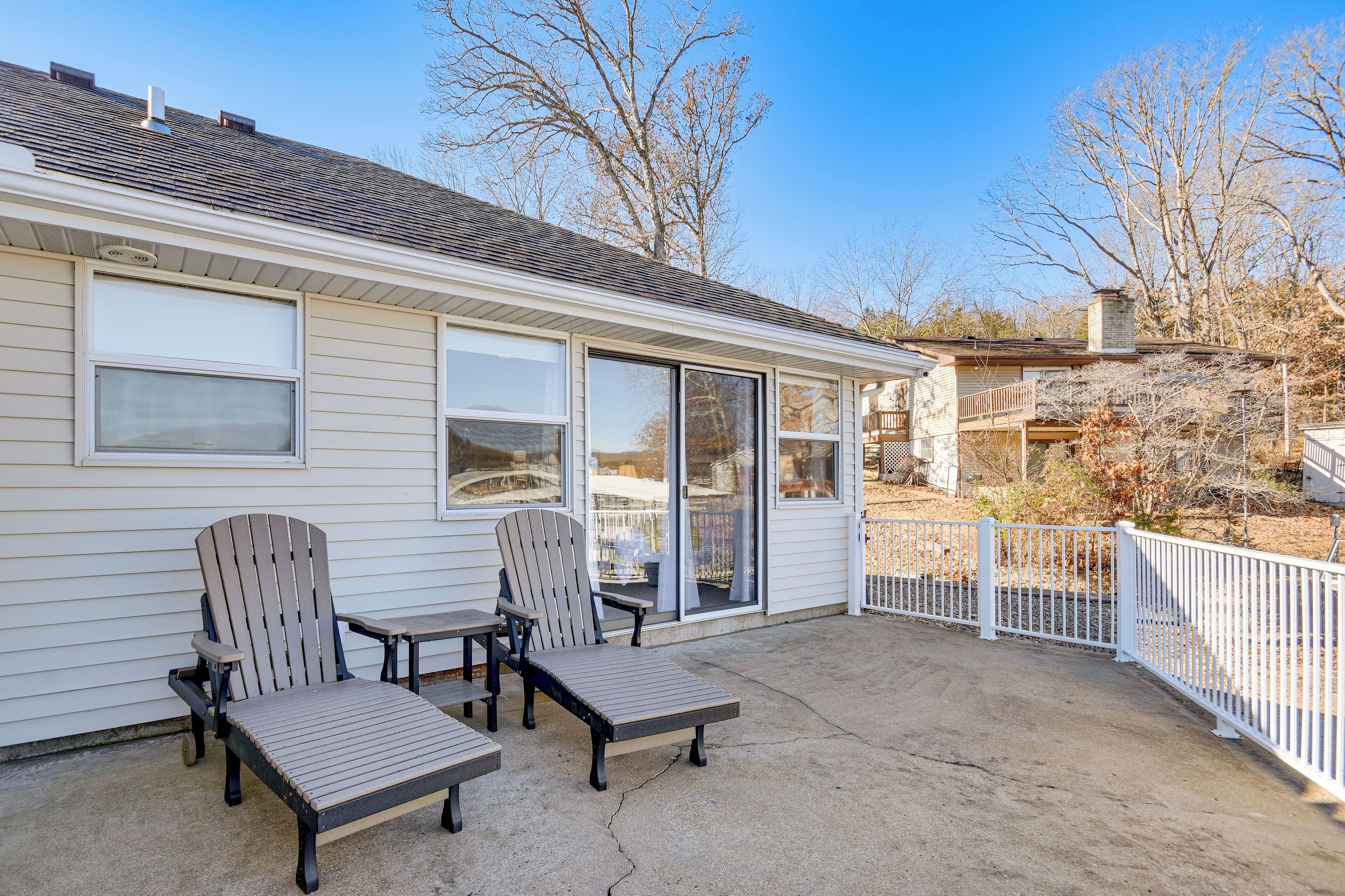 A house with a covered patio area featuring two Adirondack chairs and a small table.