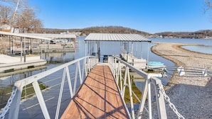 Un muelle de madera que conduce a un embarcadero con barcos, rodeado de agua tranquila y un cielo despejado.