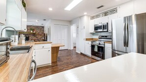 A modern kitchen with white cabinets, stainless steel appliances, and a wooden countertop. - 5 Mi to Silver Springs State Pk: Gem w/ Game Room! (Ocala)