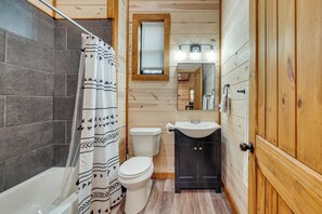 Ein Badezimmer mit Dusche, Toilette, Waschbecken und Holzwänden.