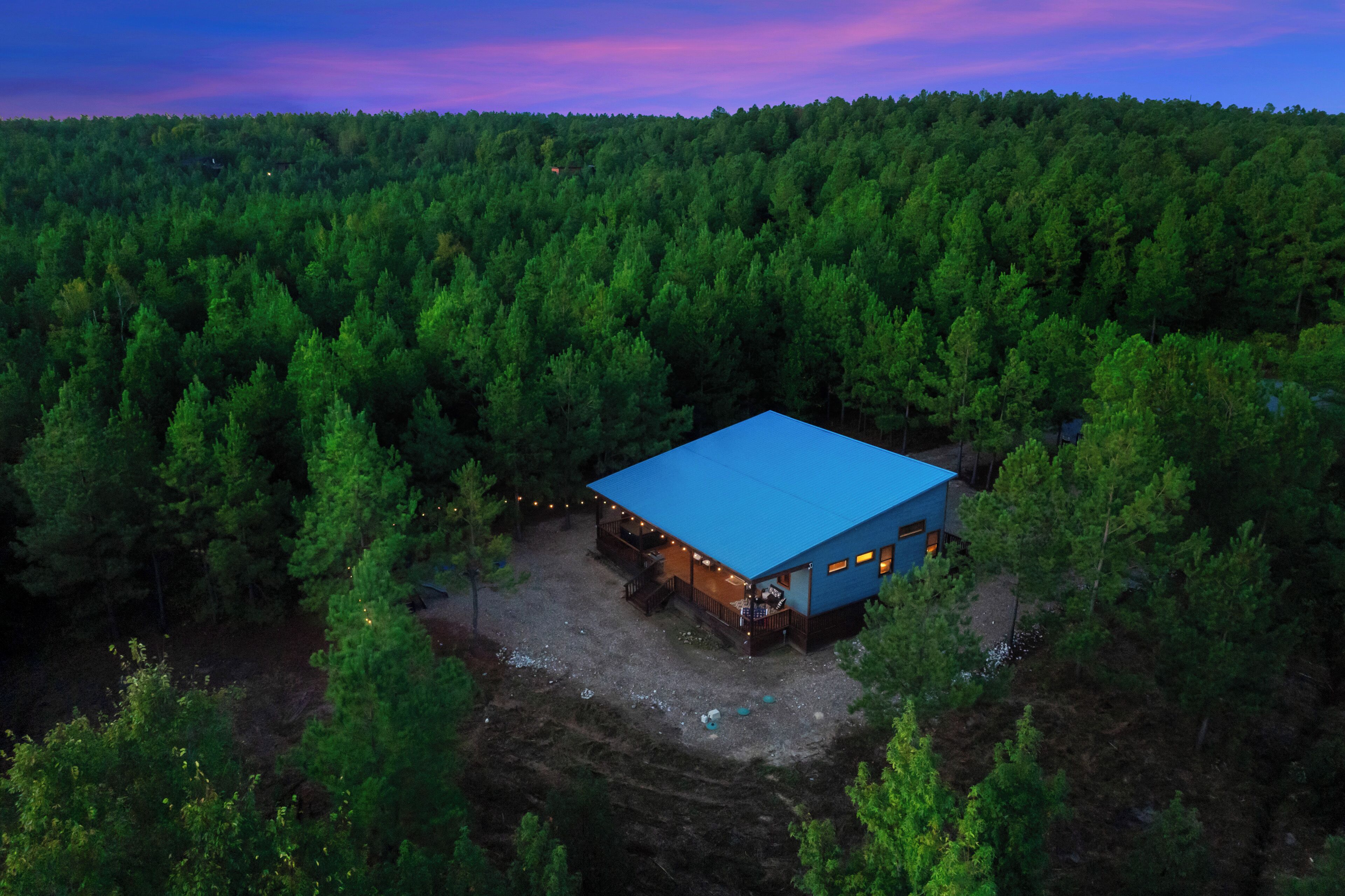 Une cabane isolée, avec un toit bleu, entourée d’une forêt dense.