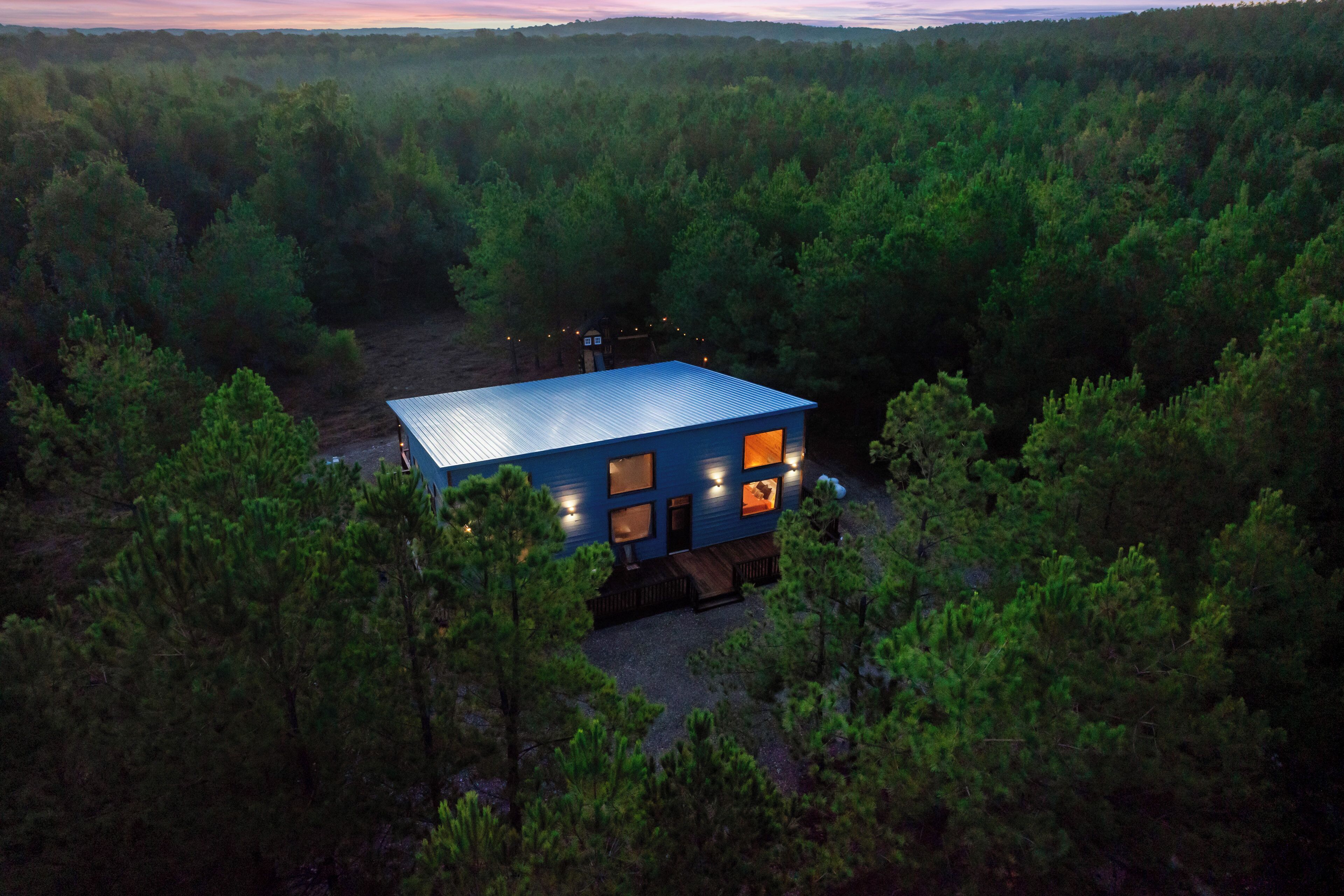 A blue cabin surrounded by dense forest.