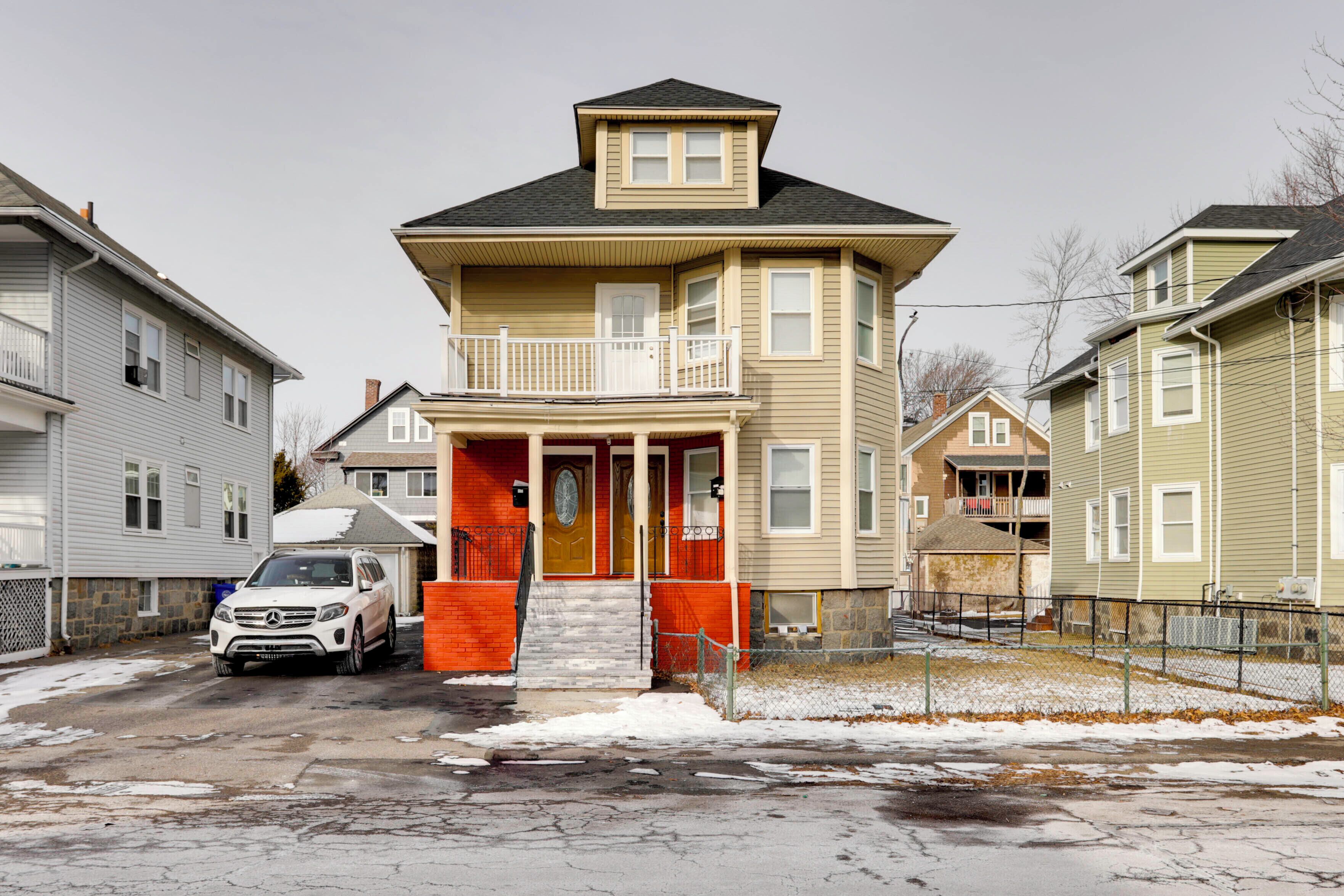 A two-story house with a balcony, a garage, and a driveway with a parked car.