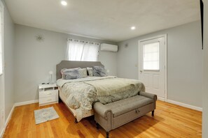 A bedroom with a bed, bedside table, bench, and a window with curtains. - 3 Mi to Blue Hills Skiing & Hiking! Couples Apt (Milton)
