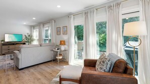 Un salon moderne avec un canapé, une table basse, un téléviseur et une lampe.