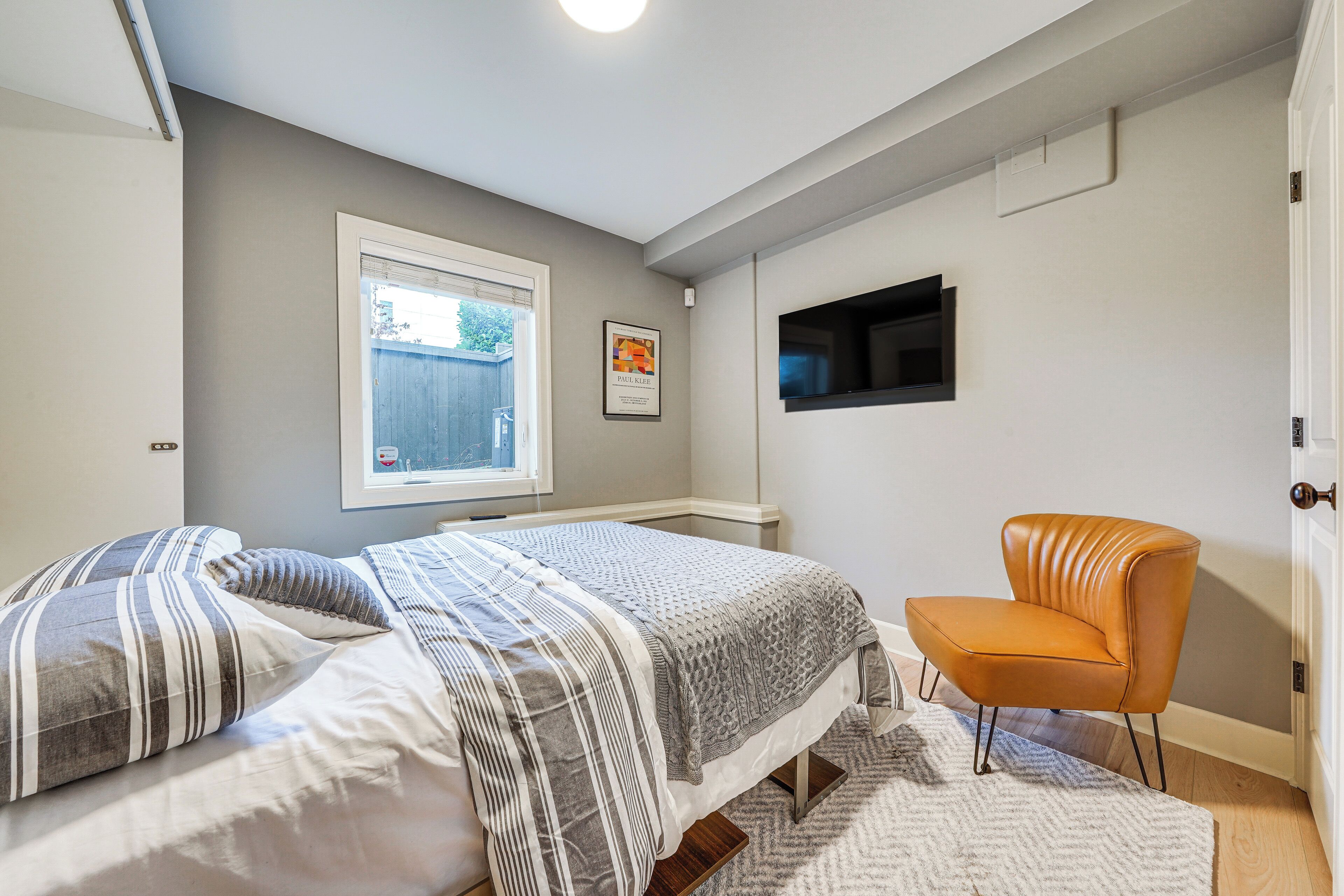 A bedroom with two beds, a chair, a TV, and a window.