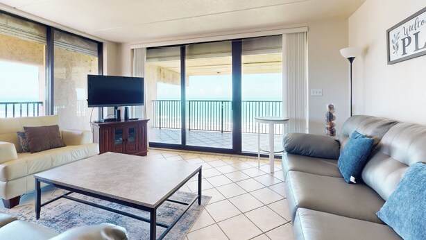 Un salon moderne avec un canapé, une table basse, un téléviseur et un balcon offrant une vue agréable.