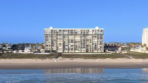 Un hôtel à plusieurs étages, doté d’un design moderne, situé juste à côté d’une plage.