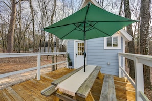 A wooden deck with a green umbrella, a white railing, and a small house with a door and windows. - Wooded Couple's Escape Near Trails & Lake Hawkins (Hawkins)