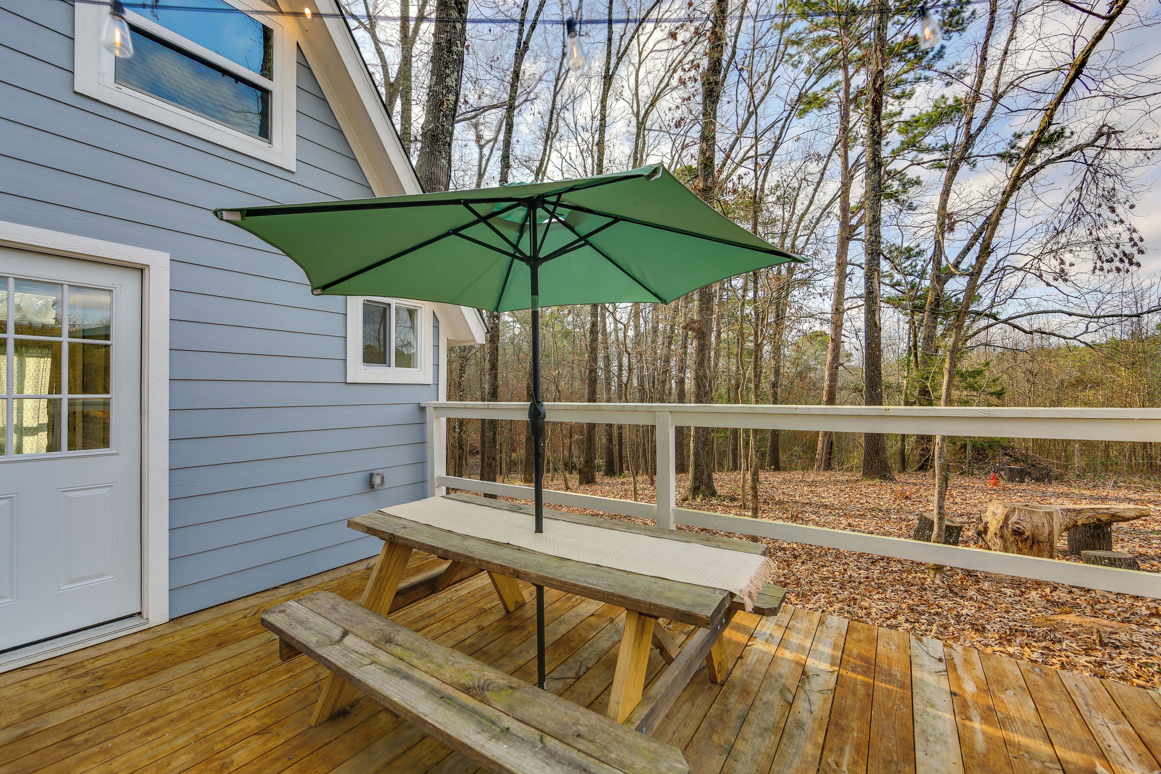 Une terrasse en bois avec une table de pique-nique et un parasol vert.