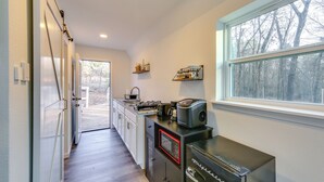 Eine Küche mit integriertem Mikrowellenherd, einer Kaffeemaschine und einem Toaster. Ein Fenster bietet Blick auf Bäume.