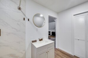 Casa de banho com uma pia branca, um espelho redondo e uma porta branca.