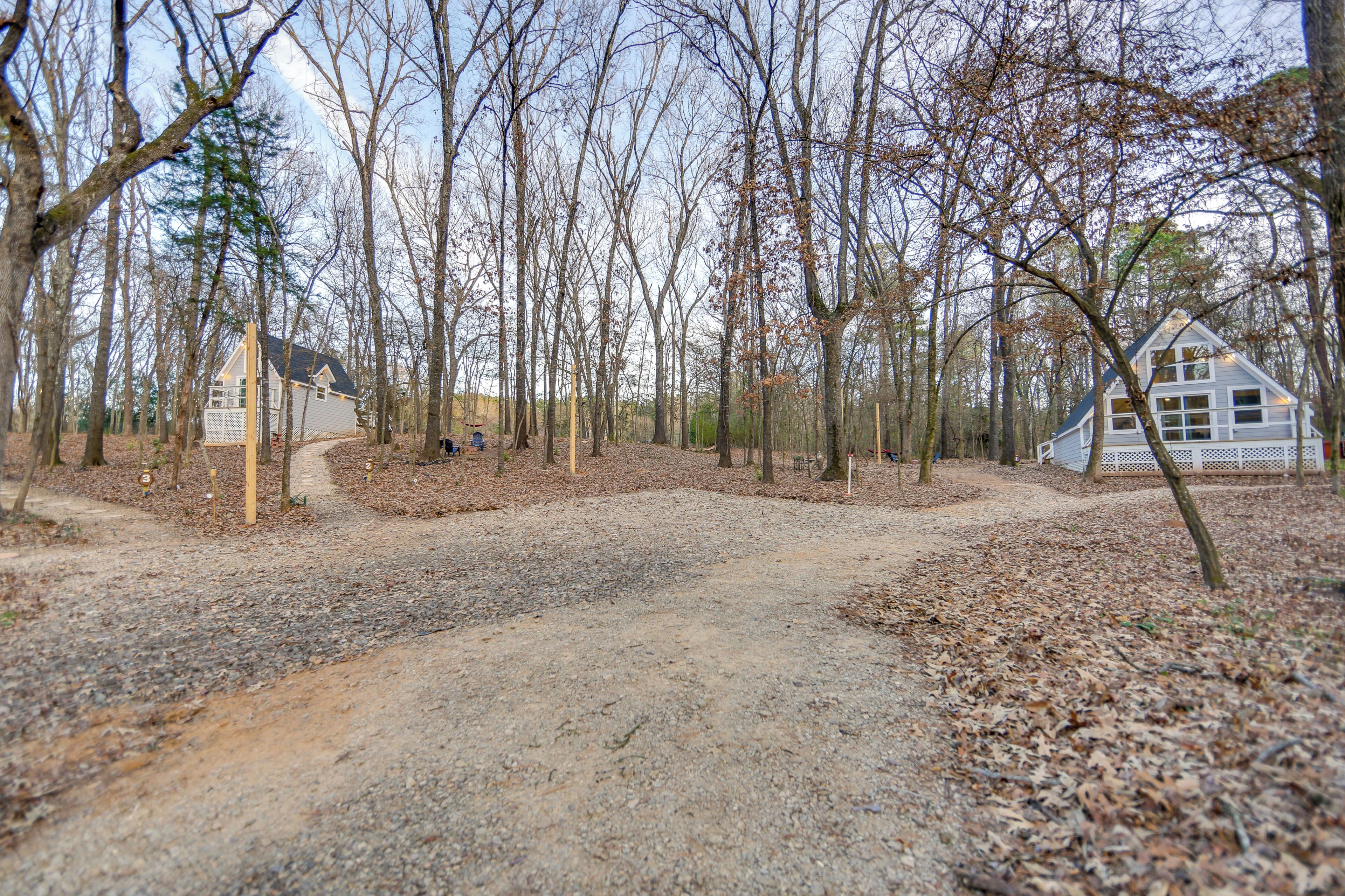 A gravel path leading to a white house surrounded by trees.