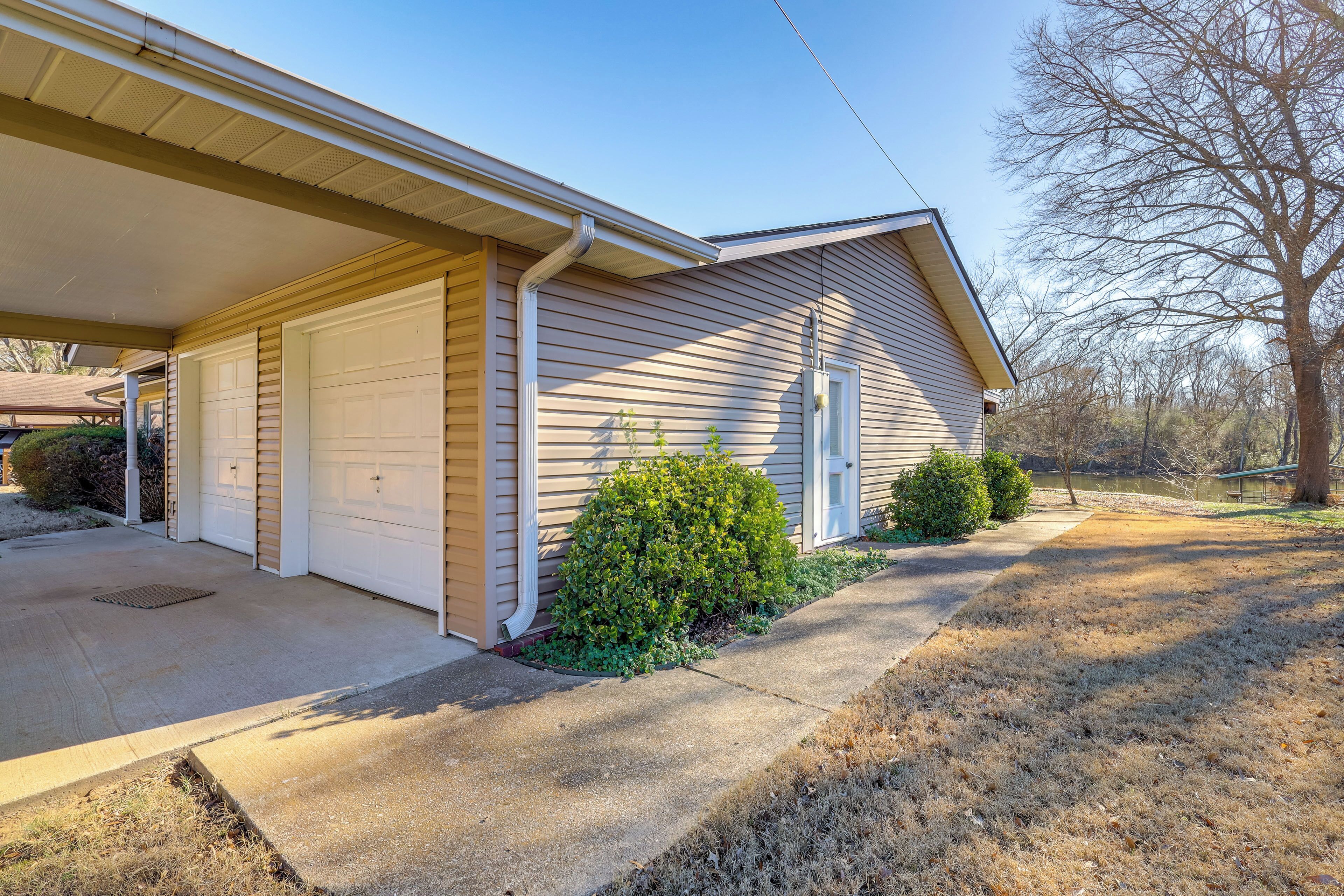 A single-story house with a garage, a covered porch, and a small front yard with a bush and a tree.