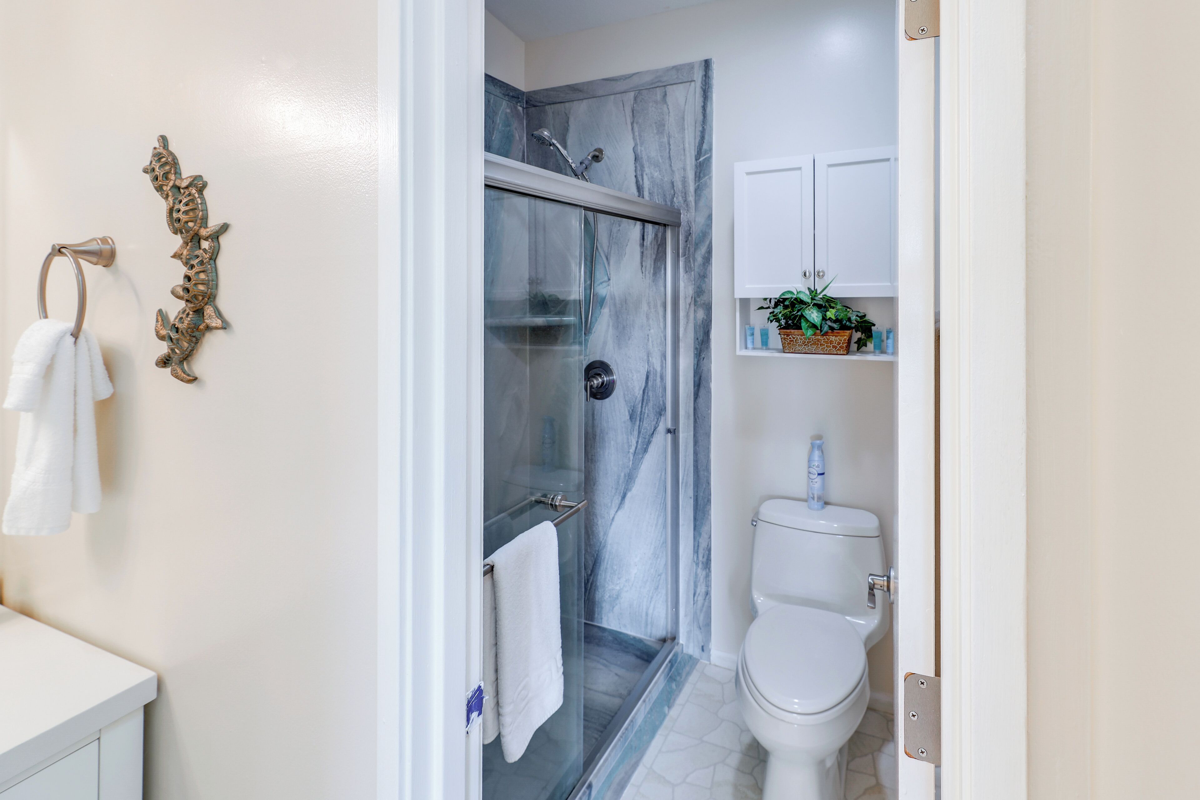 A bathroom with a glass-enclosed shower, a toilet, and a sink with a white countertop.