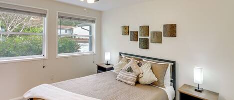 A bedroom with a bed, a nightstand, a ceiling fan, and artwork on the wall.