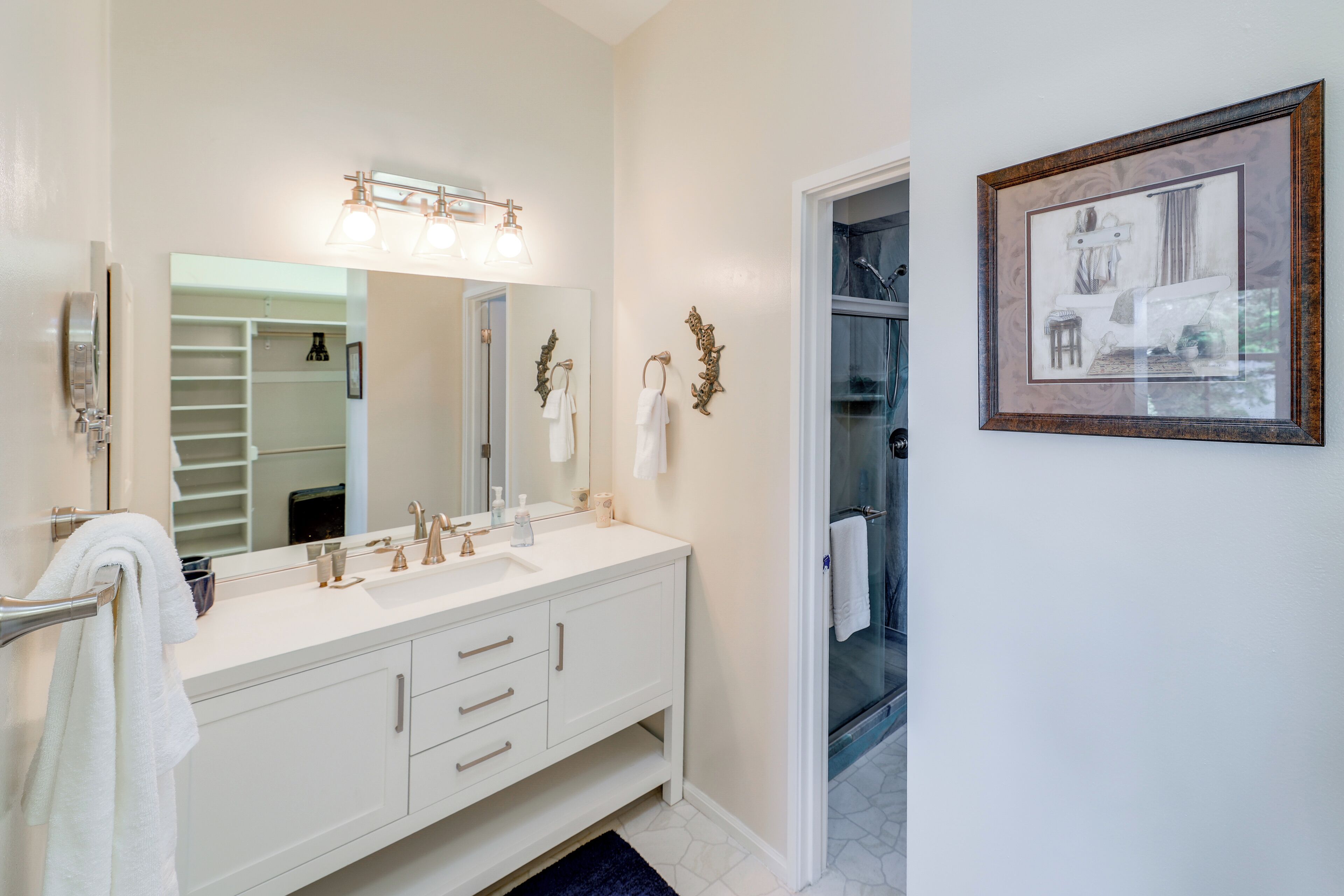 A modern bathroom with a double vanity, a large mirror, and a framed picture on the wall.