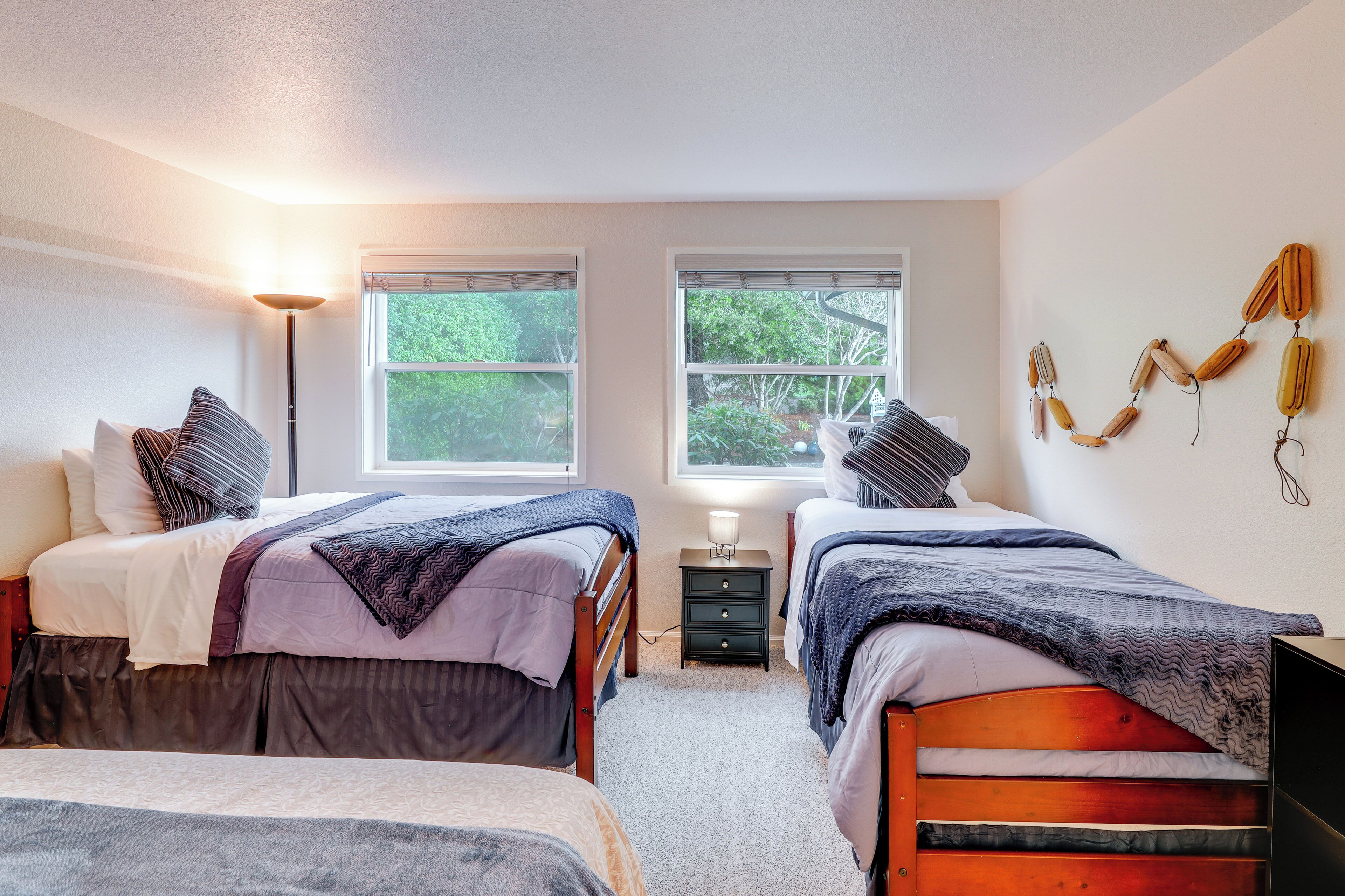 A bedroom with two beds, a nightstand, a lamp, and a wall decoration.
