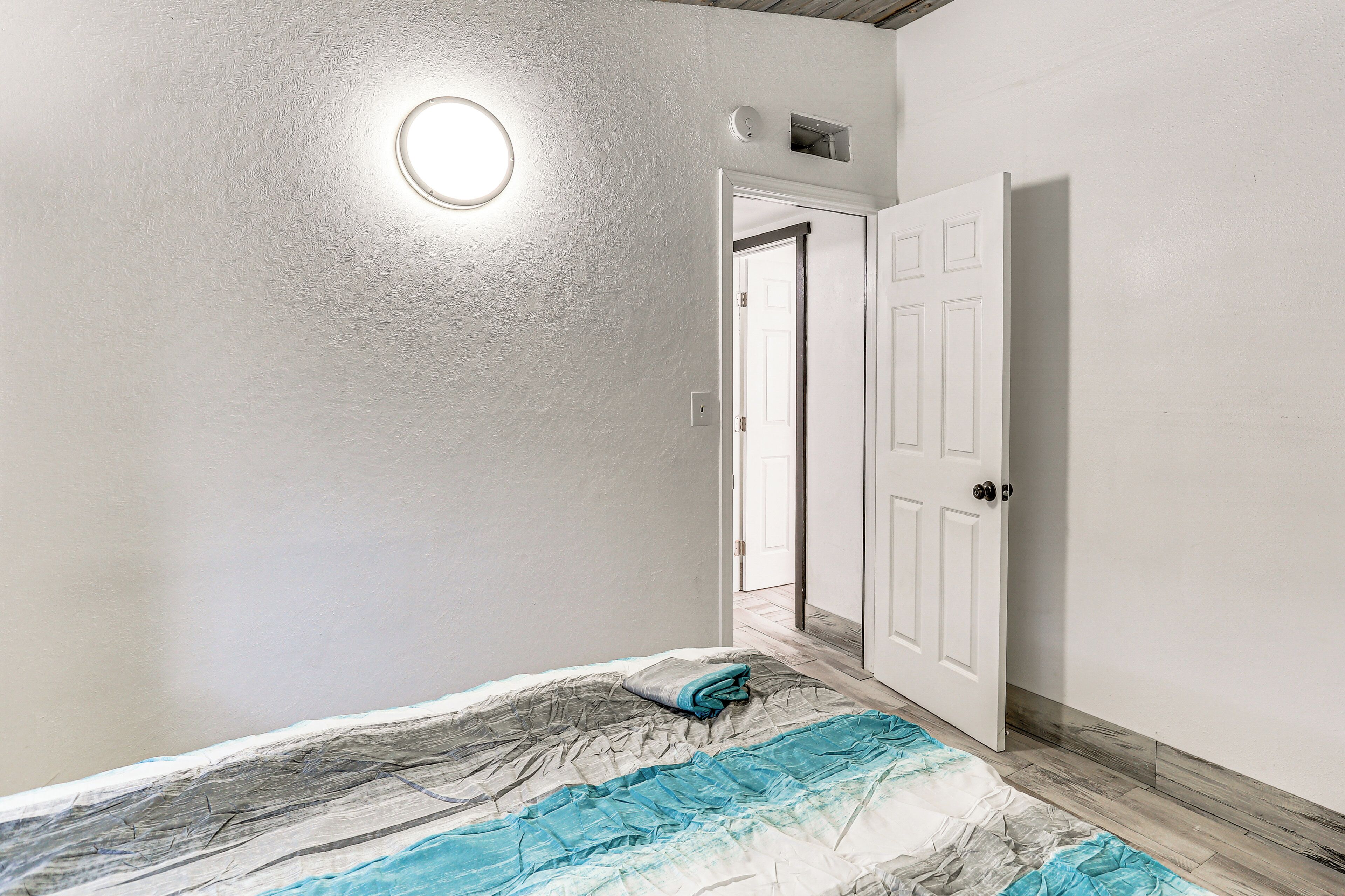 Un dormitorio con cama, una puerta y una lámpara.