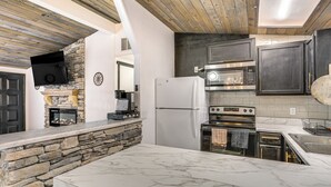 A modern kitchen with a stone accent wall, built-in appliances, and a marble countertop. - 1 Mi to Main St Eats! Single-level Red Bluff Home (Red Bluff)