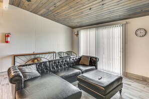 Una sala de estar con un sofá modular, un reposapiés y un reloj en la pared.