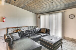 Una sala de estar con un sofá modular, un reposapiés y un reloj en la pared.