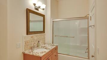 A bathroom with a sink, mirror, and shower.