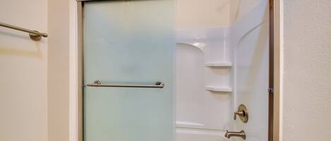 A bathroom with a glass-enclosed shower, a bathtub, and a toilet.