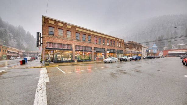 A multi-story brick building with storefronts on the ground floor, a fire hydrant, and parked cars. - Great for Skiing & Biking! Cozy Dtwn Wallace Condo (Wallace)