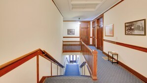 A hotel hallway with a wooden staircase, carpeted floors, and framed pictures on the walls. - Great for Skiing & Biking! Cozy Dtwn Wallace Condo (Wallace)