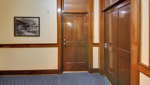 Une porte en bois portant le numéro « 2 », un tableau encadré accroché au mur et un tapis bleu recouvrant l’entrée.