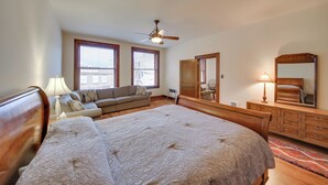 Une chambre à coucher avec un grand lit, un canapé, une commode, un miroir et un ventilateur de plafond.