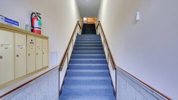 Un escalier recouvert de moquette, doté d’une rampe, d’un extincteur et d’un panneau indiquant où trouver des masques à usage unique.