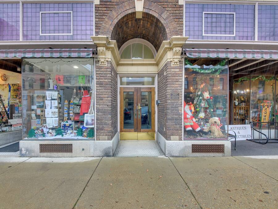 A storefront with a brick facade, large display windows, and a sign indicating it sells antiques and collectibles.