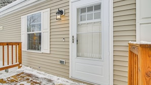 A house with a white front door, a window, and a porch with a wooden railing. - Near Trails & Vast Access! Modern Burke Home Base (East Burke)