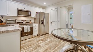 A modern kitchen with white cabinets, stainless steel appliances, and a glass dining table. - Near Trails & Vast Access! Modern Burke Home Base (East Burke)