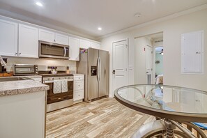 A modern kitchen with white cabinets, stainless steel appliances, and a glass dining table.