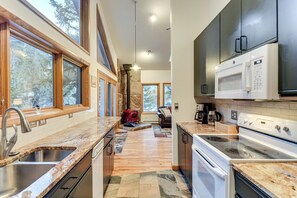 A modern kitchen with granite countertops, a built-in stove, and a stone fireplace. - Scenic Creekside Retreat! Rocky Mountain Cabin (Dumont)