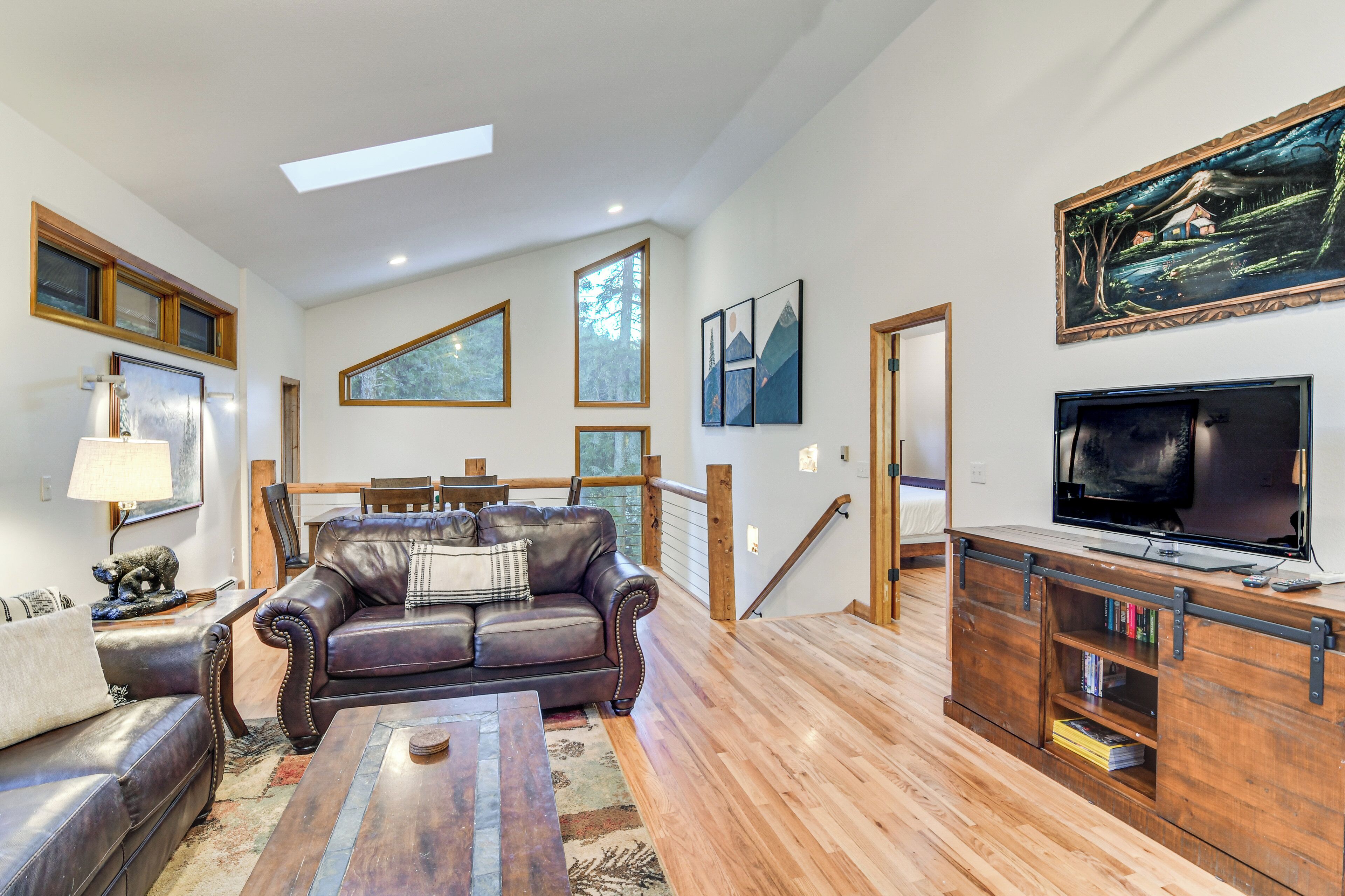 A spacious living room with a leather sofa, wooden coffee table, and a TV on a wooden stand.