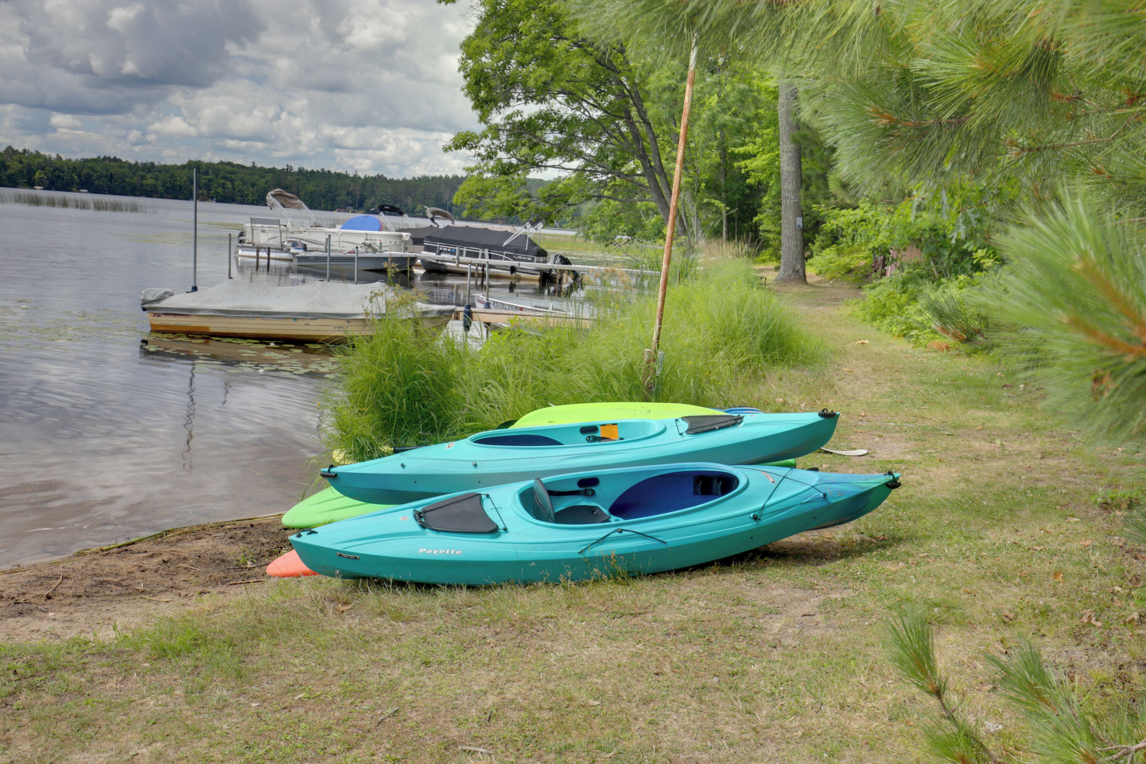 Des kayaks sont amarrés au bord d’un lac paisible, avec une jetée en arrière-plan.