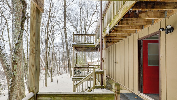 A wooden deck with a red door and a staircase leading to a second level. - George Lake Views & Access! Family Condo By Trails (Rhinelander)