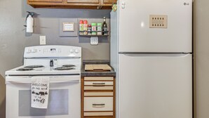 A kitchen with a white stove, oven, and refrigerator, wooden cabinets, and a spice rack. - George Lake Views & Access! Family Condo By Trails (Rhinelander)