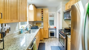 Een moderne keuken met houten kastjes, granieten aanrecht, een roestvrijstalen koelkast en een inbouwoven.